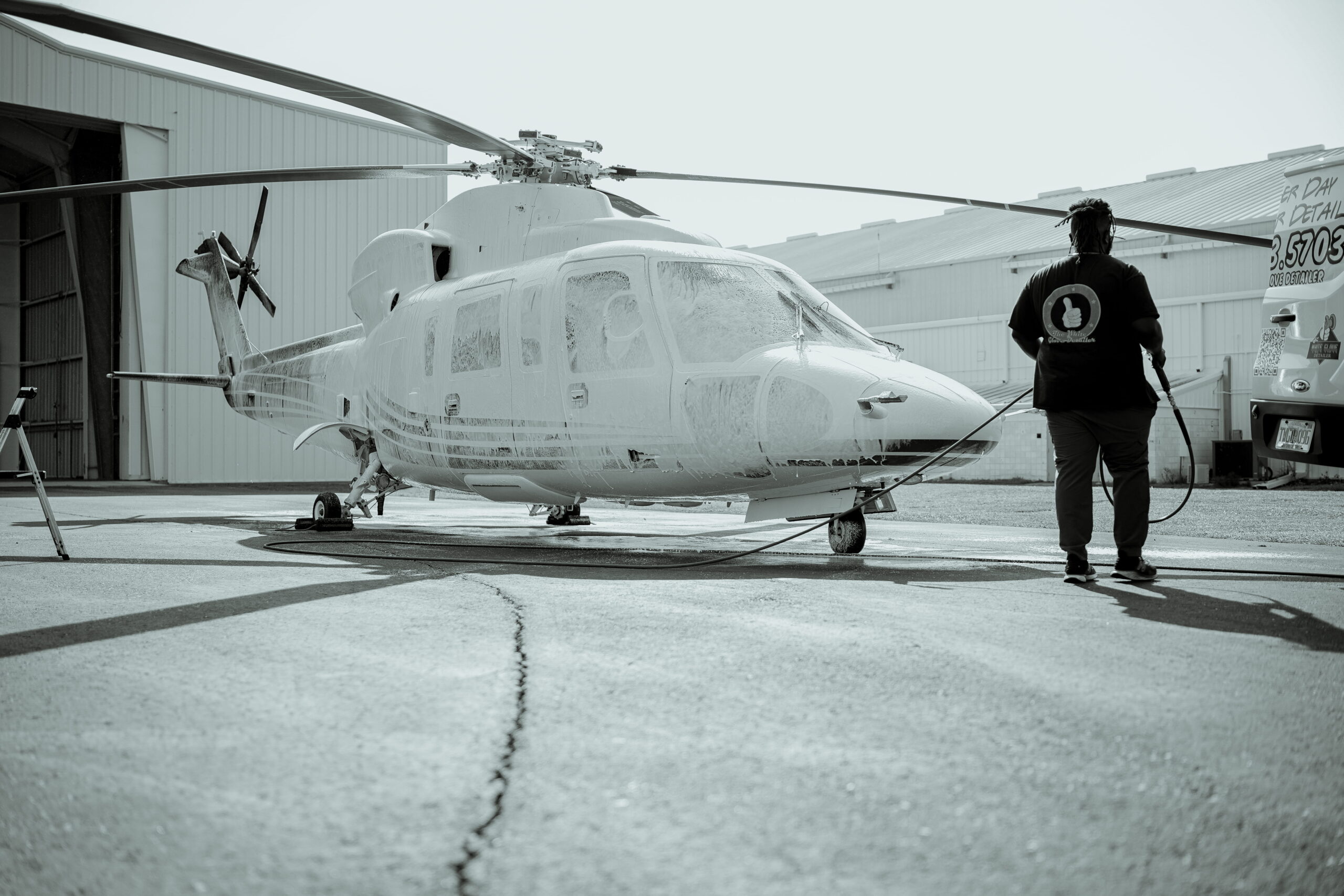 Detailer walking toward a helicopter in a Tampa Bay hangar for aviation detailing